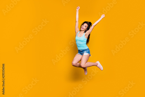 Full length body size photo of overjoyed cute excited youngster jumping up with victorious glory wearing jeans denim shorts with hands up making fists isolated vivid color background