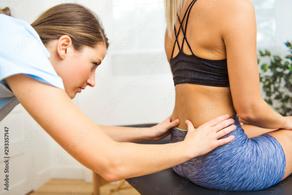 A Modern rehabilitation physiotherapist at work with client. working on lower back. A Modern rehabilitation physiotherapist at work with client. working on lower back.
