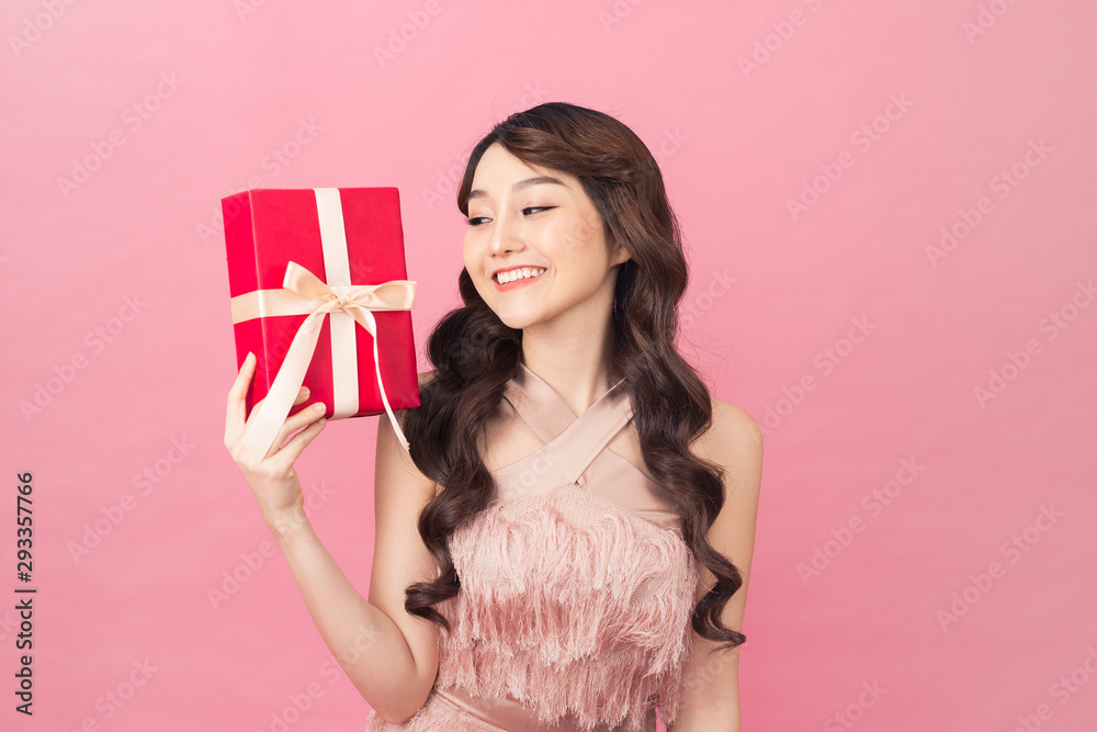 Young woman holding gift box with biege bow being excited and surprised holiday present Young woman holding gift box with biege bow being excited and surprised holiday present