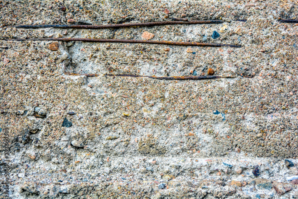 Texture of crumbling concrete wall with horizontal bars of rusty iron