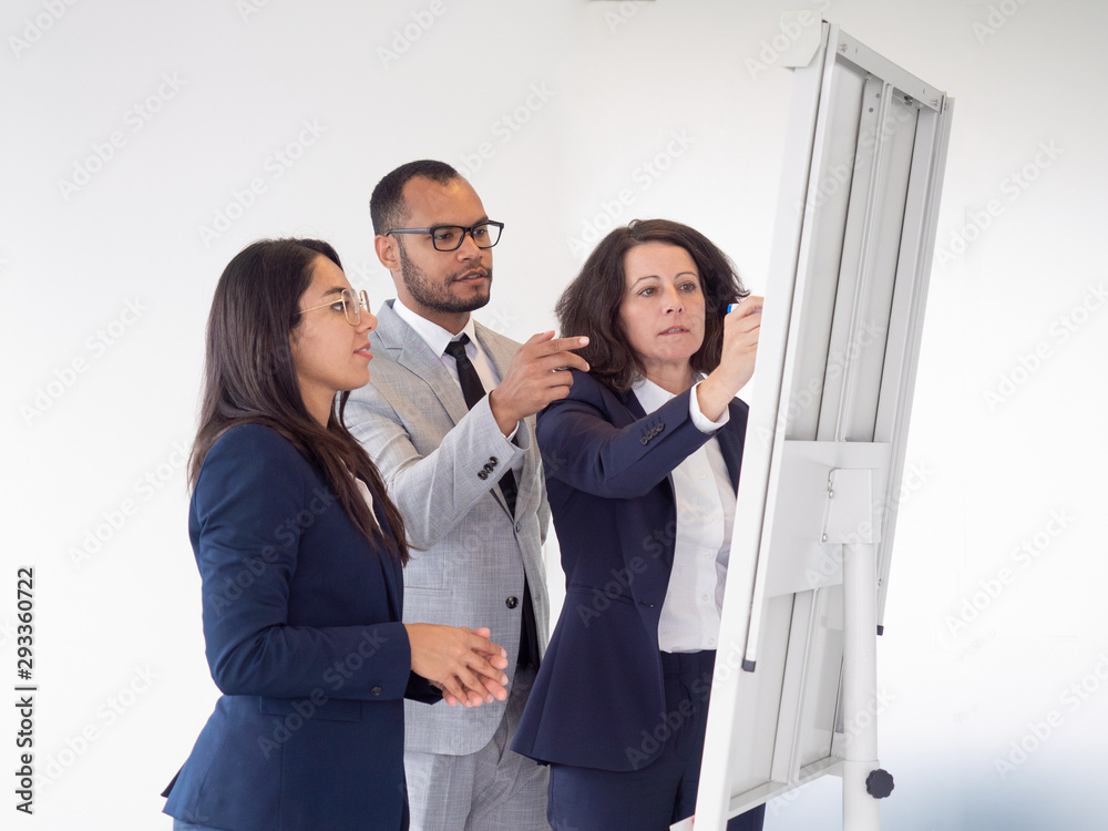 Professional business team working with whiteboard. Multiethnic group of business people in formal wear standing together and writing on whiteboard. Teamwork concept Professional business team working with whiteboard. Multiethnic group of business people in formal wear standing together and writing on whiteboard. Teamwork concept
