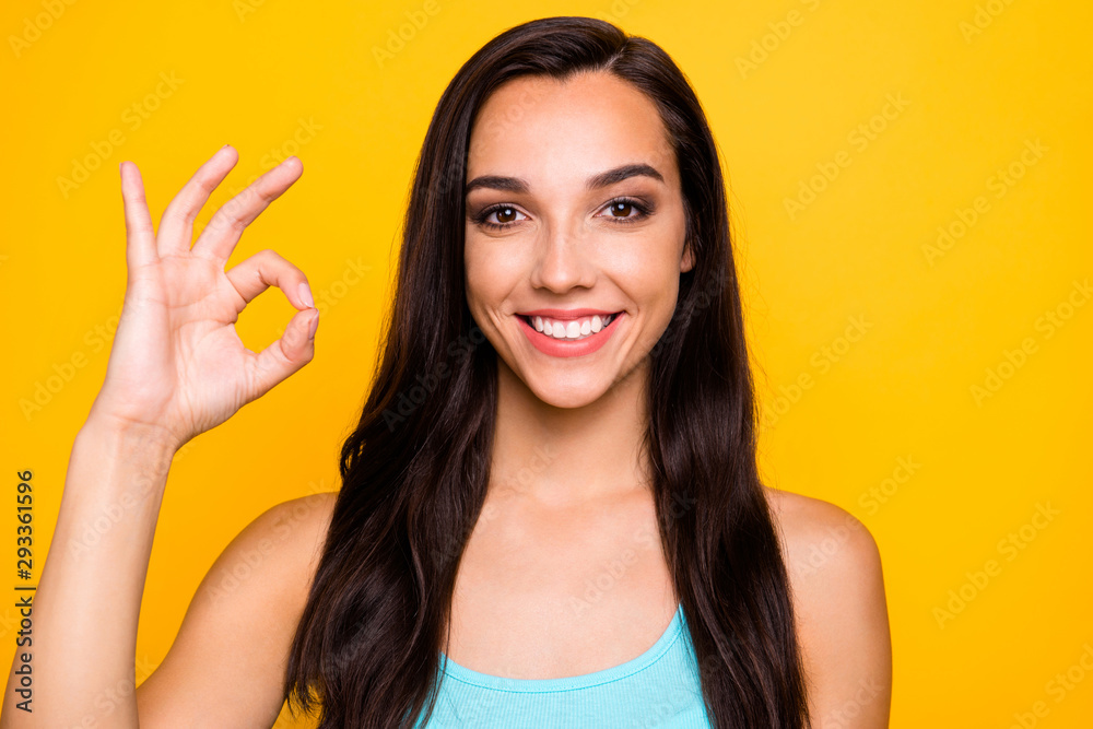 Close up photo of charming attractive young promoter showing you ok sign in order to show perfect quality of adverted production wearing turquoise singlet isolated over yellow vibrant color background Close up photo of charming attractive young promoter showing you ok sign in order to show perfect quality of adverted production wearing turquoise singlet isolated over yellow vibrant color background