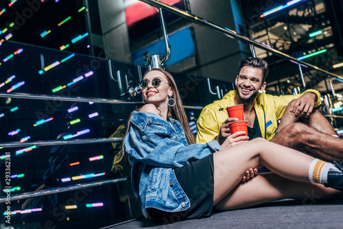 handsome boyfriend and attractive girlfriend with plastic cups smiling in night city © LIGHTFIELD STUDIOS