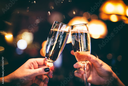 Two glasses with sparkling champagne wine in hands, concept for holiday, wedding valentines Christmas and New Year, bokeh, in a restaurant and cafe