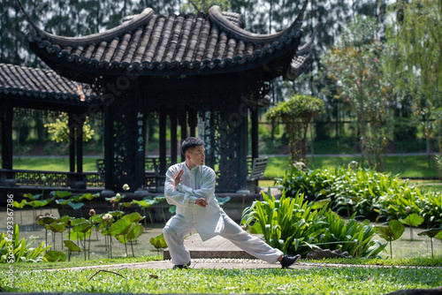 Asian man working out with Tai Chi in the morning at the park, Chinese martial arts, healthy care for life concept. photo