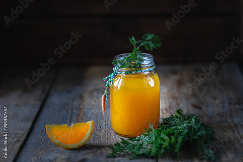 Healthy food. Carrots and carrot juice with orange in a glass jar in a metal basket on a dark wooden background