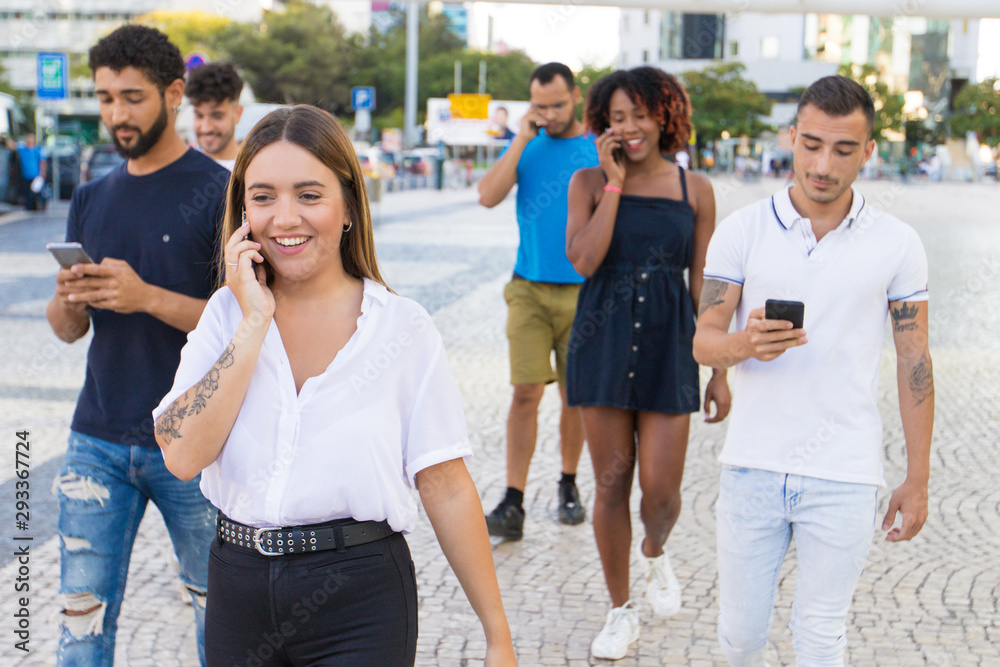 Happy excited woman talking on cell while walking down city street. Mix raced men and women going outside, talking on cells, using mobile phones. Smartphone using concept Happy excited woman talking on cell while walking down city street. Mix raced men and women going outside, talking on cells, using mobile phones. Smartphone using concept