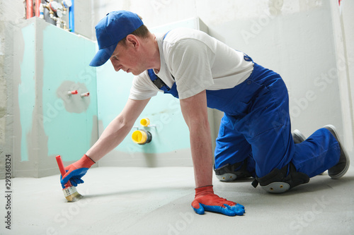Floor waterproofing in bathroom. Worker adding цater resistant, protective coating photo