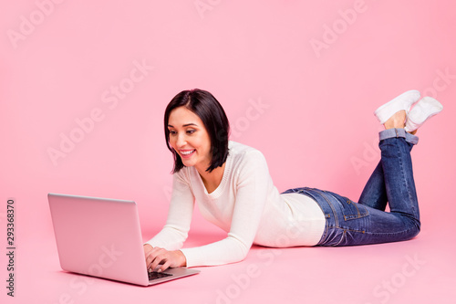 Full body photo of charming lady lying floor making homework using notebook wear white pullover and jeans isolated pink color background
