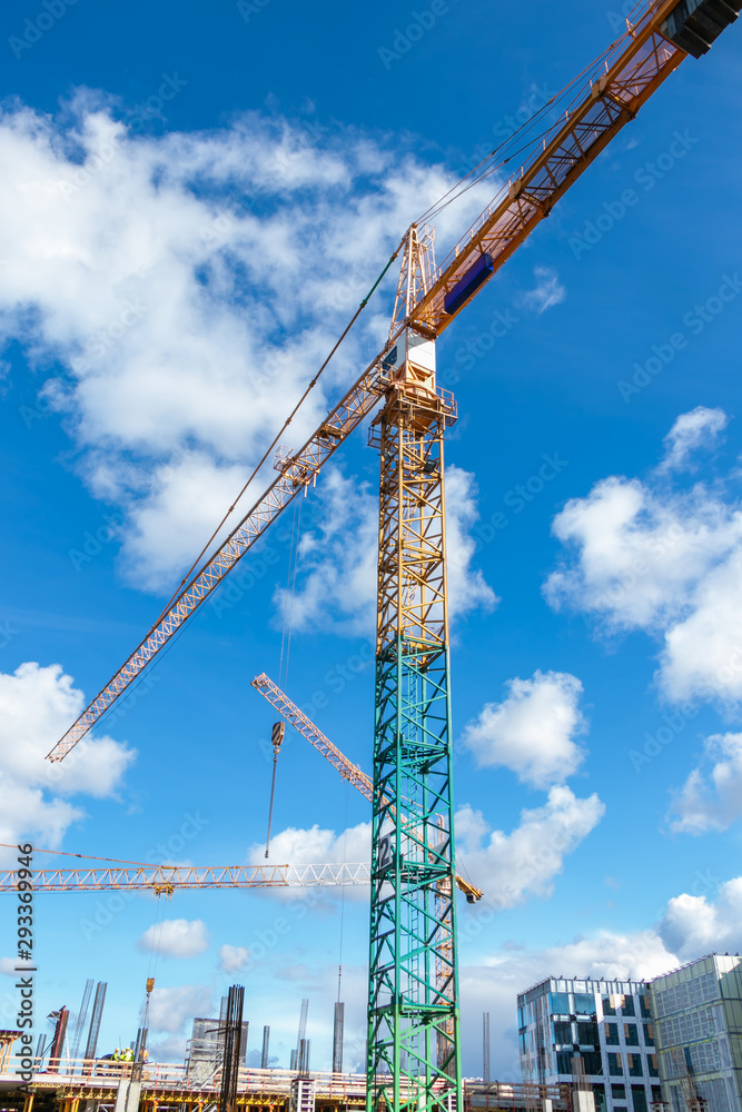 close up of a cranes at construction site in sunny day with blue sky and white clouds.