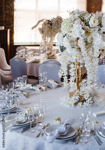 banquet round tables, decorated with a bouquet of white flowers in the center of the tables