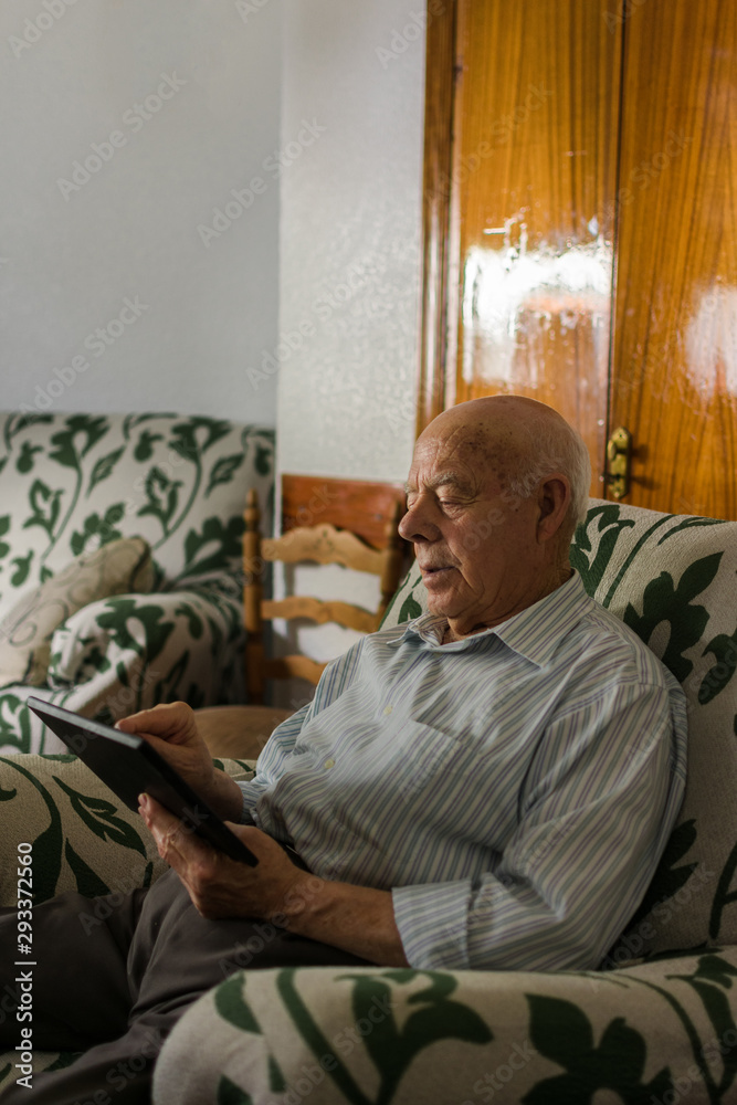 Elderly man is using a digital tablet at home Elderly man is using a digital tablet at home