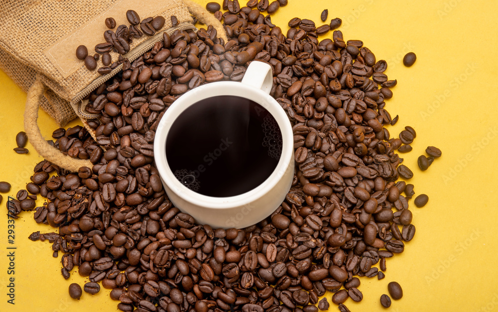 Cup of coffee beans and burlap sack on yellow background, copy space banner Cup of coffee beans and burlap sack on yellow background, copy space banner