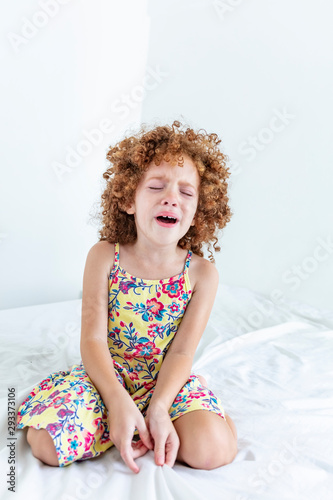 Beautiful sad girl crying in bed after sleepover, fell bouncing