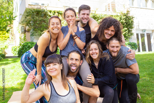 Yoga group smiling at camera. Happy young men and women in sportswear gathering together and smiling at camera in park. Yoga concept