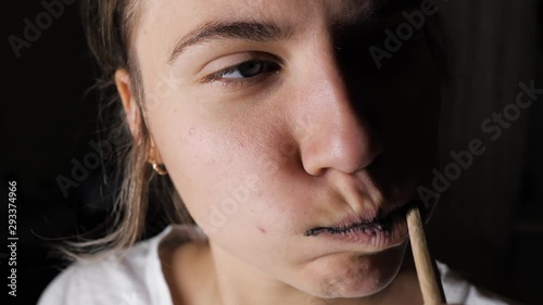 A woman brushes her teeth with black whitening paste with charcoal, a bamboo eco-friendly toothbrush made of wood.
