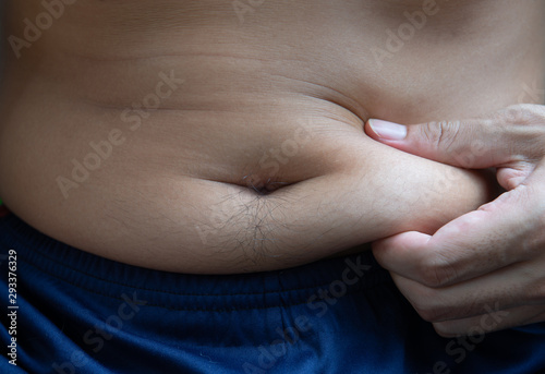 Man is use the hand to holding the fat on the belly photo