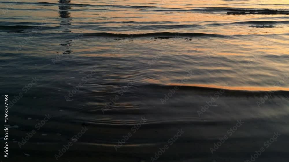 Reflection of a couple walking at sunset in the Baltic Sea on waves landing on LIepaja beach in the Courland of Latvia Reflection of a couple walking at sunset in the Baltic Sea on waves landing on LIepaja beach in the Courland of Latvia