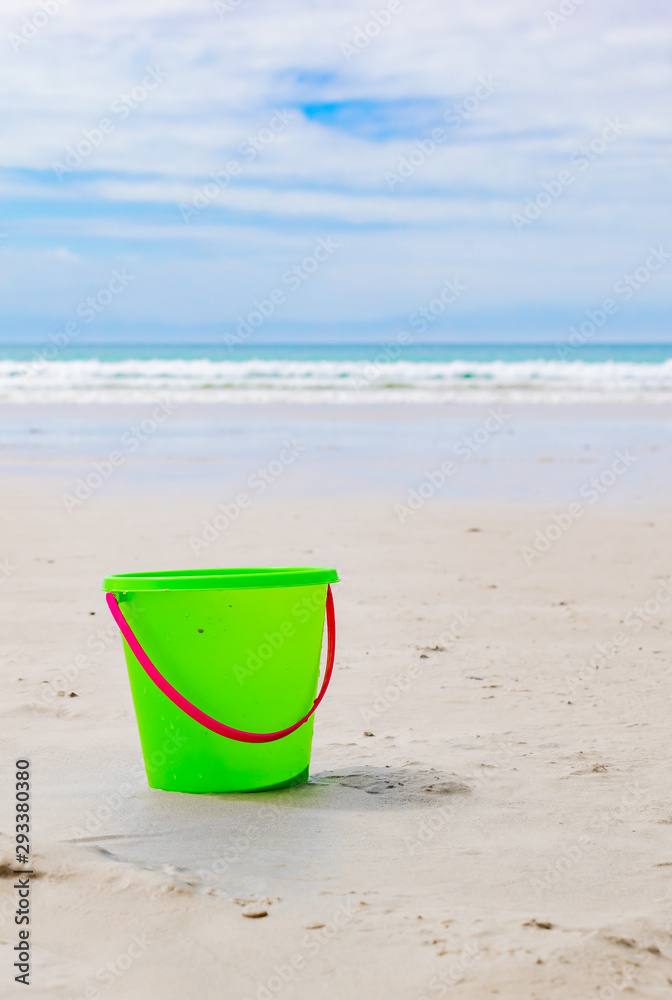 Plastic Kids Bucket for making sandcastles on a sandy beach Plastic Kids Bucket for making sandcastles on a sandy beach