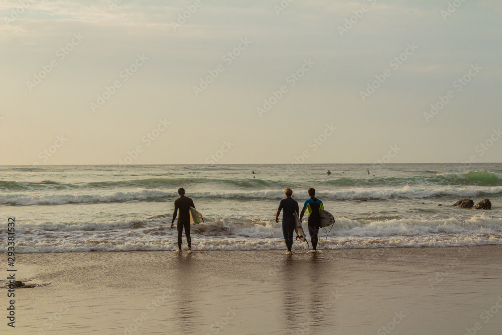 three surfers about to get into the water at Barrika Beach three surfers about to get into the water at Barrika Beach
