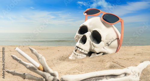 concept about cigarette addiction a skeleton with a cigarette lies on the beach © Jens Rother