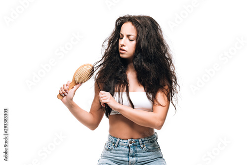 brunette woman styling unruly curly hair with hairbrush isolated on white photo