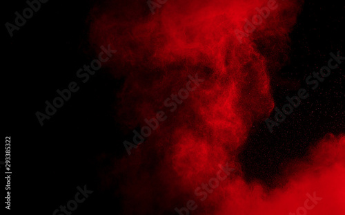 Fototapeta Wybuch proszku koloru czerwonego na czarnym tle. Zamroź ruch rozpryskiwania cząstek czerwonego pyłu.