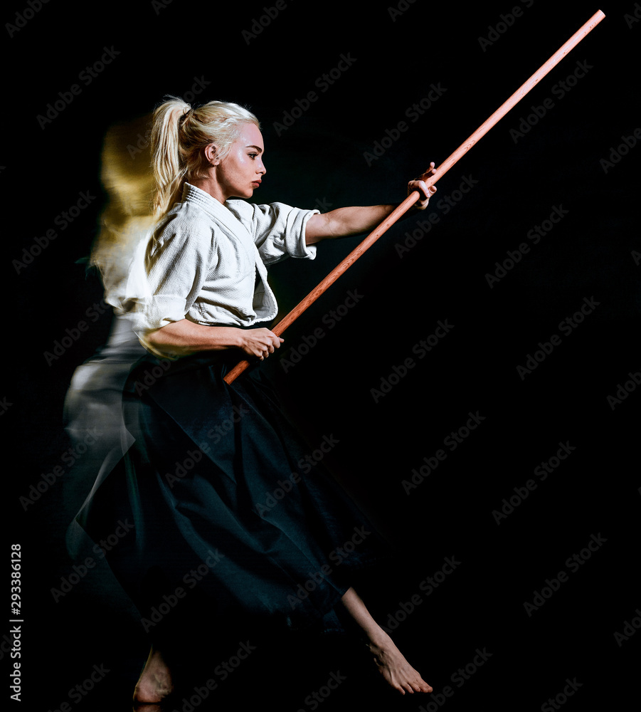 one caucasian bodoka fighters woman practicing Bo-Jutsu studio shot isolated on black background one caucasian bodoka fighters woman practicing Bo-Jutsu studio shot isolated on black background