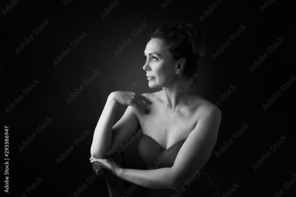 Portrait of a sensual fifty year old woman on grey studio background. Monochrome shot. Portrait of a sensual fifty year old woman on grey studio background. Monochrome shot.