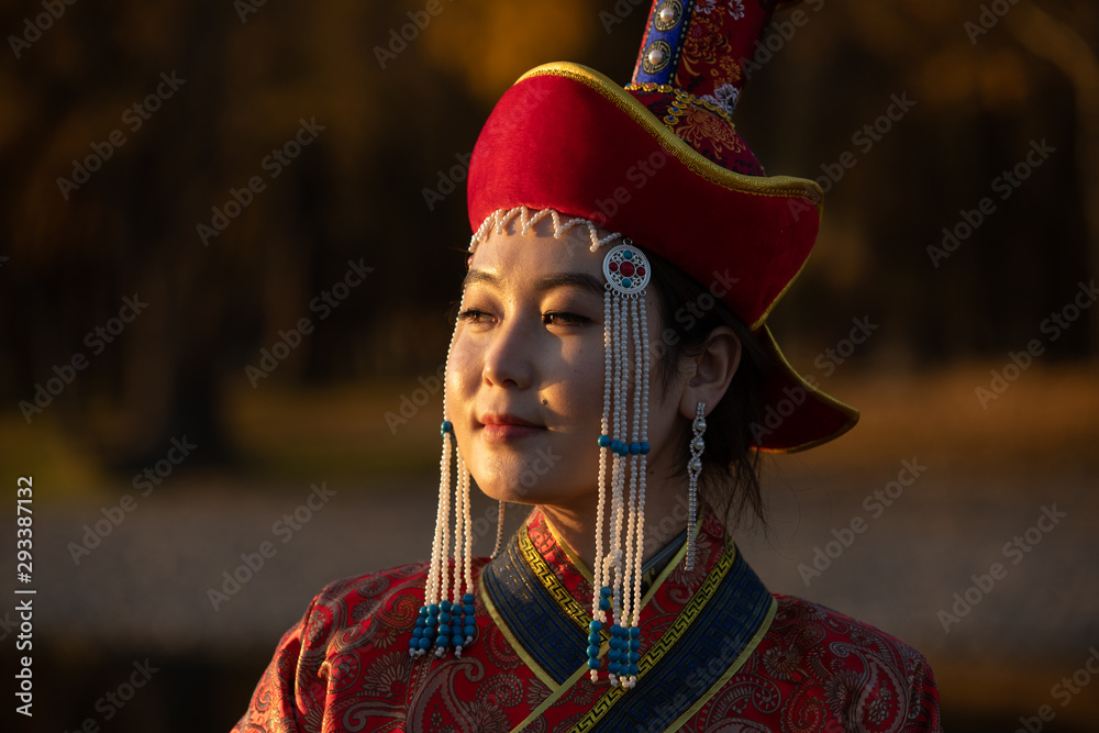 Beautiful young woman posing in traditional Mongolian dress in sunset light. Ulaanbaatar, Mongolia.