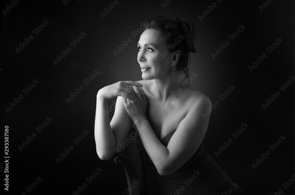 Portrait of a sensual fifty year old woman on grey studio background. Monochrome shot. Portrait of a sensual fifty year old woman on grey studio background. Monochrome shot.
