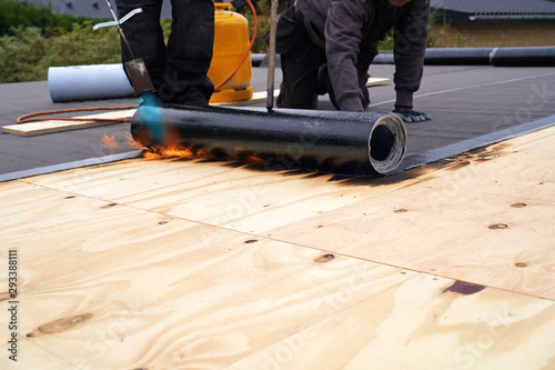 Bitumen roofing.,  with a gas burner and a roll of tar paper. Flat roof installation.