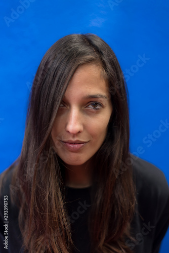 Portrait of brunette woman standing against blue wall