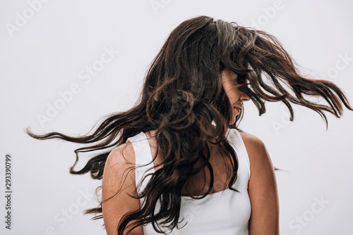 brunette beautiful woman with long healthy and shiny hair waving head isolated on grey