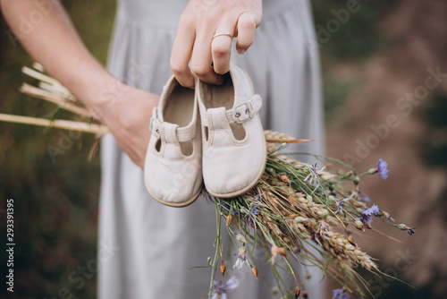 Close up photo of young mother holding baby shoes