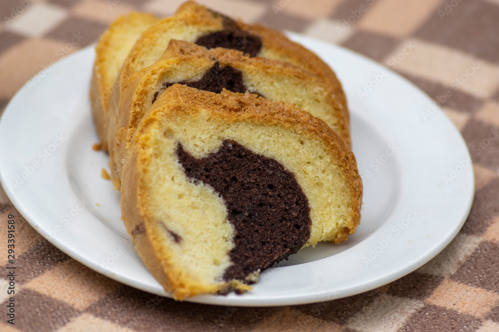 Gugelhupf on white plate on picnic blanket, very tasty edible two-colored Czech sweet cake called babovka, sliced ready to eat Gugelhupf on white plate on picnic blanket, very tasty edible two-colored Czech sweet cake called babovka, sliced ready to eat