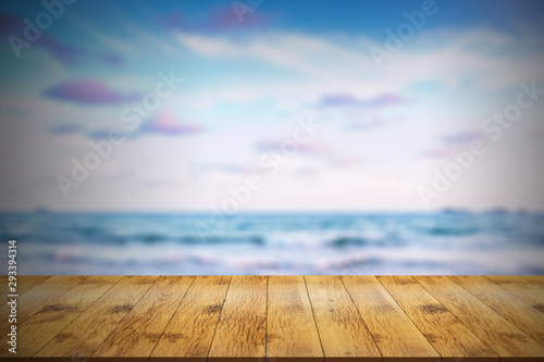Empty wooden table in front with blurred background of sea view.