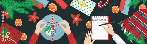Girl packs a Christmas gift and ties a bow. A girl writing a wish list. Flat lay with Christmas tree branch, gift and oranges