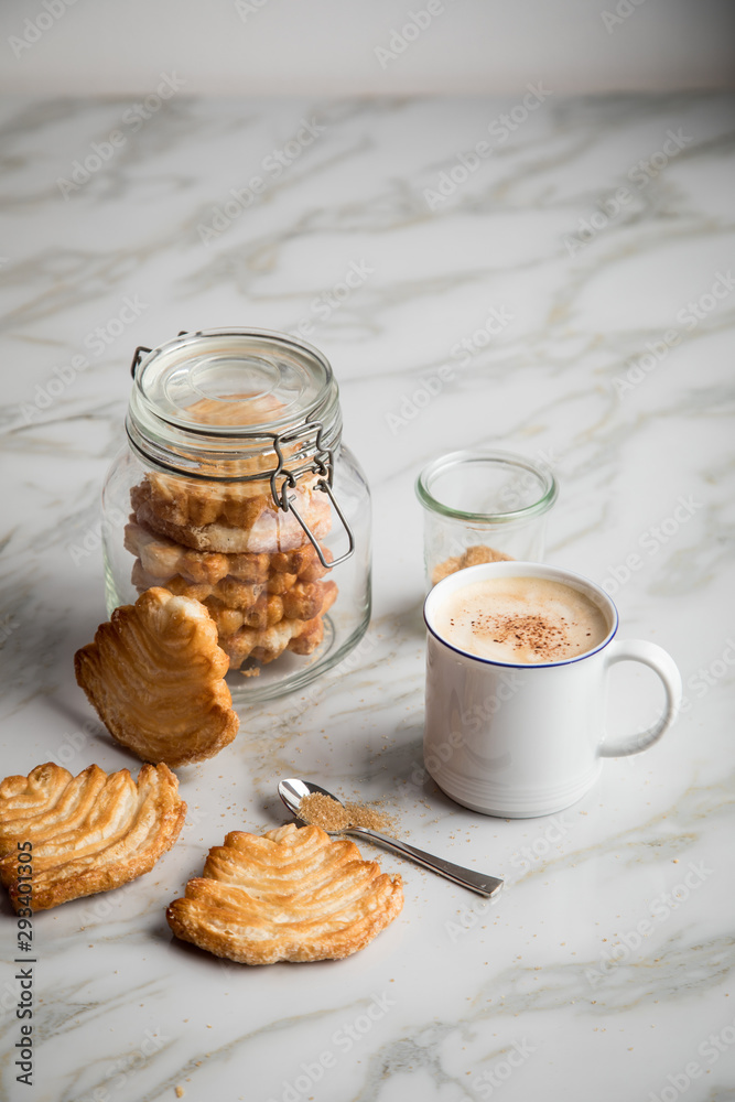 Italienische Blätterteig Fächer Kekse mit Einmachglas und Becher Kaffee auf Marmor Hintergrund Italienische Blätterteig Fächer Kekse mit Einmachglas und Becher Kaffee auf Marmor Hintergrund