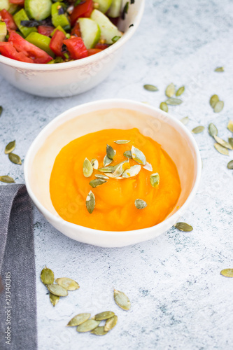 Cooked yellow pumpkin puree with pumpkin seeds in bowl. Vegan, vegetarian. Creamy.