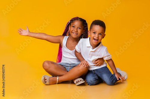 Adorable little sister and brother sitting on floor and cuddling