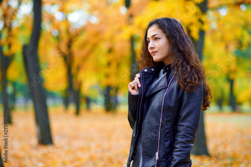 woman posing with autumn leaves in city park, outdoor portrait