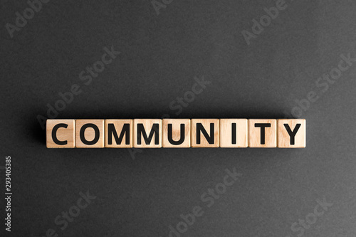 Community - word from wooden blocks with letters, group of people community concept, random letters around, top view gray background