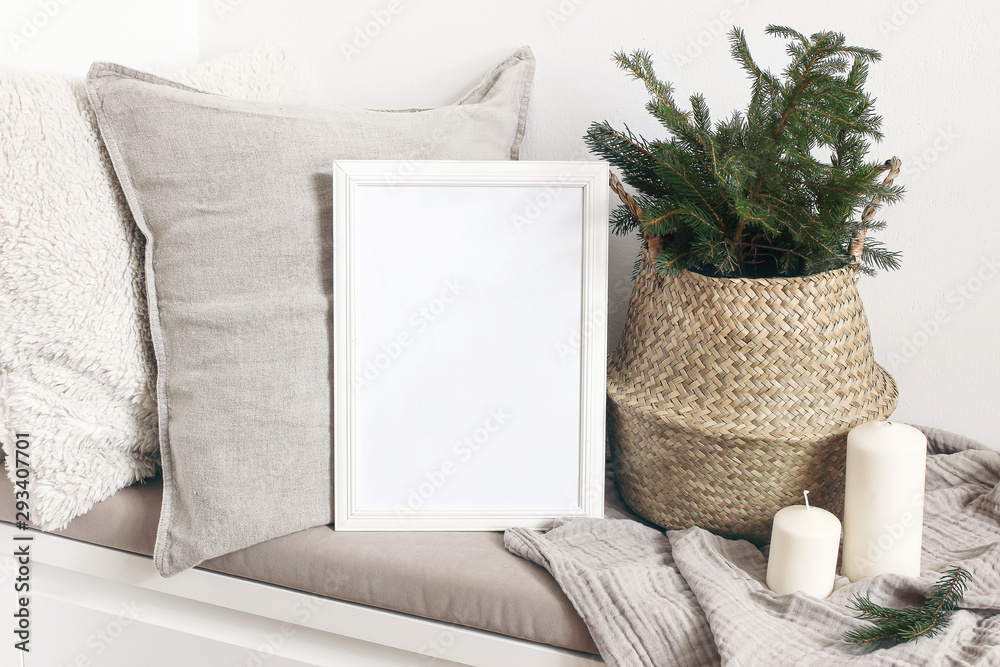 White blank wooden frame mockup with Christmas tree, candles, linen cushions and plaid on the white bench. Poster product design. Scandinavian home decor, nordic design. Winter festive concept. - obrazy, fototapety, plakaty 