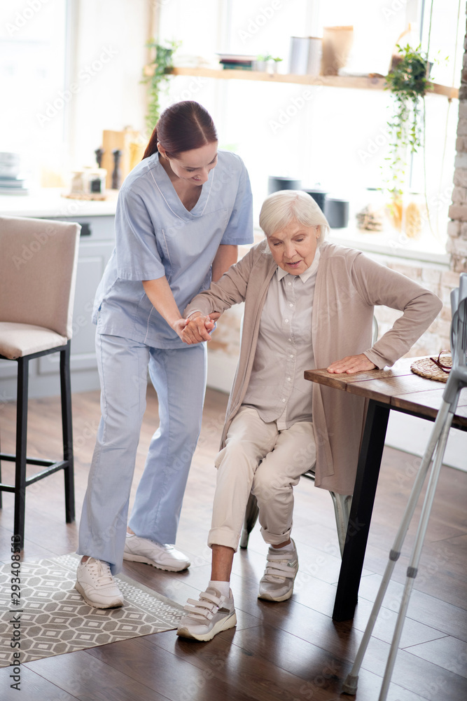 Nurse assisting aged woman in making steps after surgery Nurse assisting aged woman in making steps after surgery