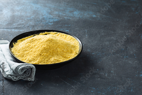 Yellow pea flour in black ceramic bowl on dark background with copy space photo