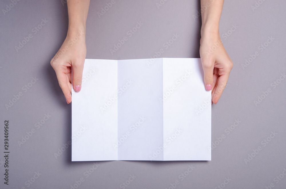 Empty flyer sheets in hand on grey background, top view. Mockup for design Empty flyer sheets in hand on grey background, top view. Mockup for design