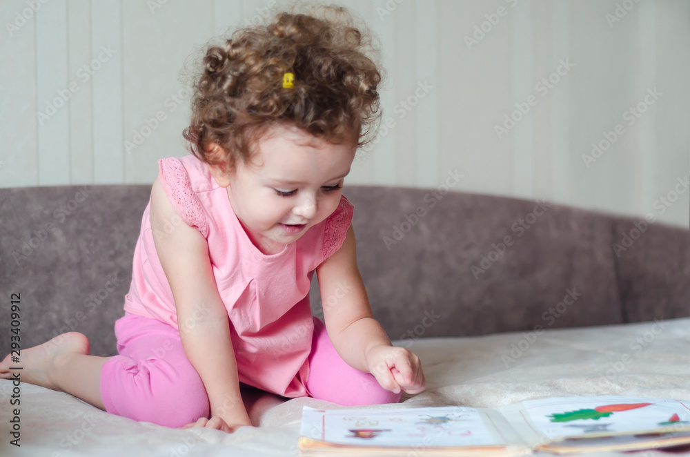 Cute girl reading book at home. the child shows an interesting picture. soft focus Cute girl reading book at home. the child shows an interesting picture. soft focus