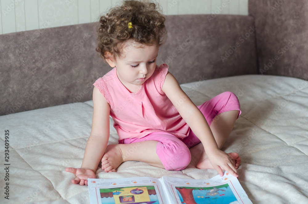 Cute girl reading book at home. the clever child is considering interesting pictures. Cute girl reading book at home. the clever child is considering interesting pictures.