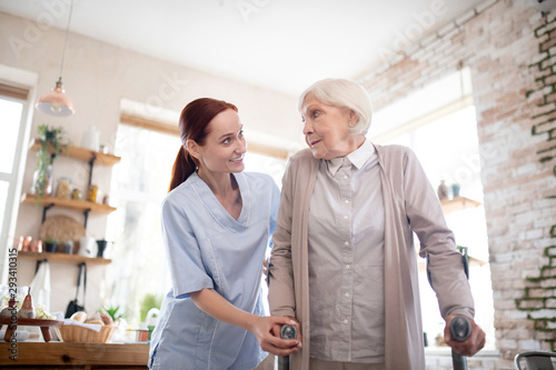 Red-haired caregiver supporting woman with crutches